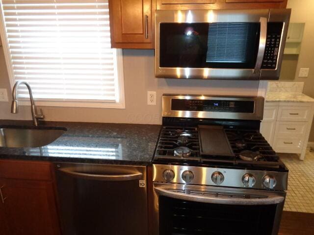905-907 Beech St, Columbus, OH 43206 - kitchen featuring stainless steel appliances, a sink, dark stone countertops, and brown cabinets