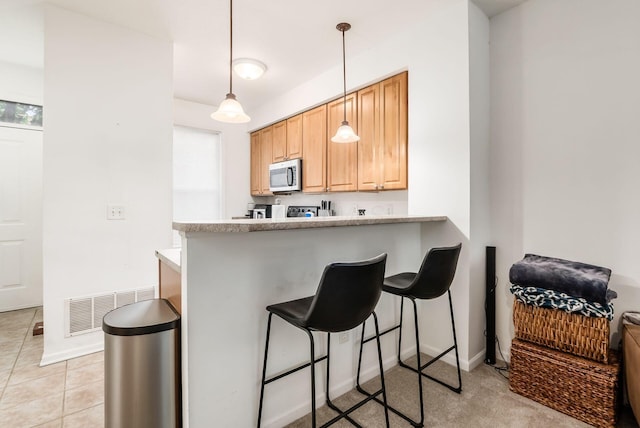 797 S Front St, Columbus, OH 43206 - kitchen with stainless steel microwave, a breakfast bar area, light countertops, and decorative light fixtures