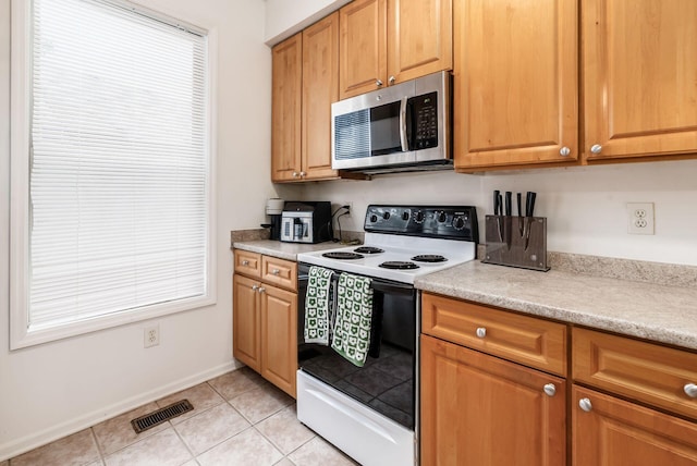 797 S Front St, Columbus, OH 43206 - kitchen with range with electric cooktop, stainless steel microwave, light tile patterned flooring, light countertops, and baseboards