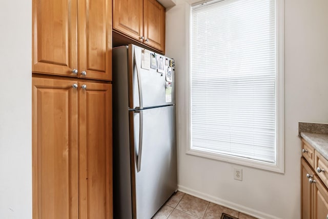 797 S Front St, Columbus, OH 43206 - kitchen featuring freestanding refrigerator, light tile patterned flooring, brown cabinetry, and baseboards