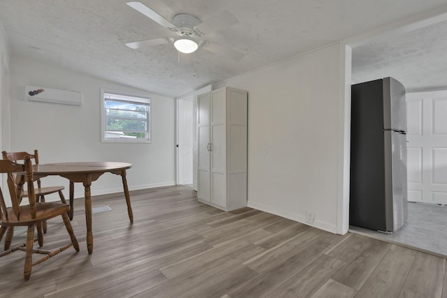 663 E Mound St, Circleville, OH 43113 - dining space featuring an AC wall unit, light wood finished floors, vaulted ceiling, ceiling fan, and a textured ceiling