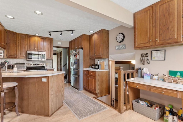6799 Thrasher Ct, Orient, OH 43146 - kitchen with stainless steel appliances, light wood-style flooring, backsplash, and brown cabinets
