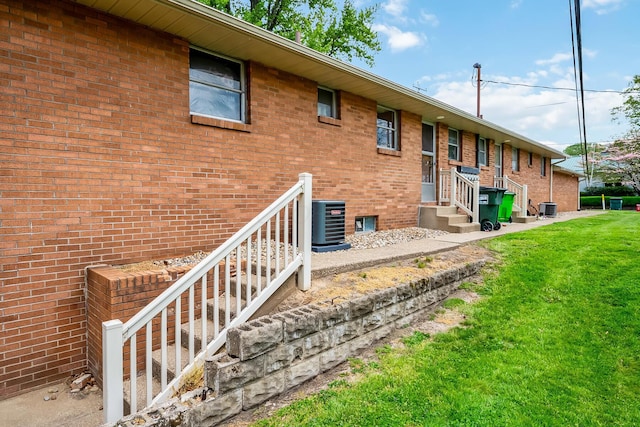 320 N 3rd St, Coshocton, OH 43812 - back of house with central air condition unit, a lawn, and brick siding