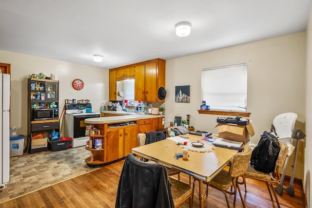 320 N 3rd St, Coshocton, OH 43812 - kitchen with white appliances, a peninsula, brown cabinetry, and light countertops