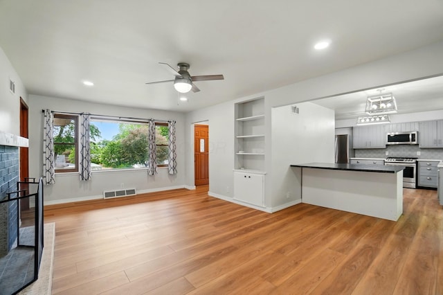 1244 N Broad St, Lancaster, OH 43130 - unfurnished living room with light wood finished floors, ceiling fan, a tile fireplace, baseboards, and built in shelves