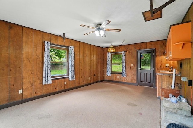 1244 N Broad St, Lancaster, OH 43130 - unfurnished living room with light carpet, ceiling fan, wooden walls, a sink, and baseboards
