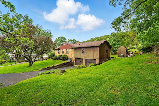 1244 N Broad St, Lancaster, OH 43130 - view of side of home with a garage, asphalt driveway, a yard, central AC, and a storage shed
