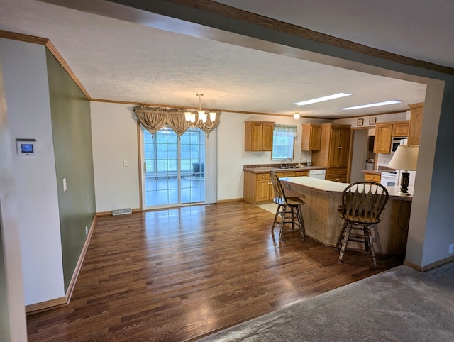 284 Camp Creek Rd, Lucasville, OH 45648 - kitchen with a chandelier, dark wood-type flooring, a peninsula, baseboards, and a breakfast bar