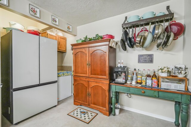 1235 Canteberry Ln, Mansfield, OH 44906 - kitchen with freestanding refrigerator, a textured ceiling, and brown cabinets
