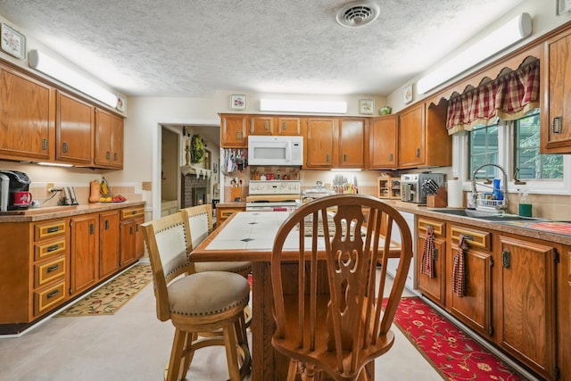 1235 Canteberry Ln, Mansfield, OH 44906 - kitchen featuring white appliances, a sink, a textured ceiling, brown cabinets, and light countertops