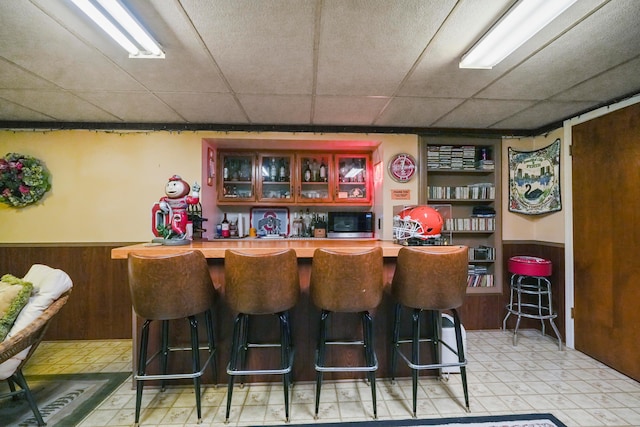 1235 Canteberry Ln, Mansfield, OH 44906 - indoor dry bar with light floors, stainless steel microwave, a drop ceiling, wood walls, and a wainscoted wall