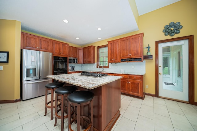 390 Engelwood Ct, Powell, OH 43065 - kitchen featuring appliances with stainless steel finishes, decorative backsplash, a center island, light stone counters, and a kitchen bar