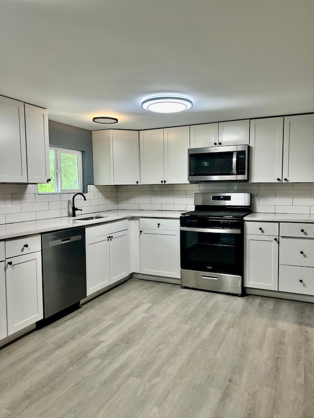 13212 Maple Rd NE, Thornville, OH 43076 - kitchen with stainless steel appliances, a sink, tasteful backsplash, light wood-style floors, and light countertops