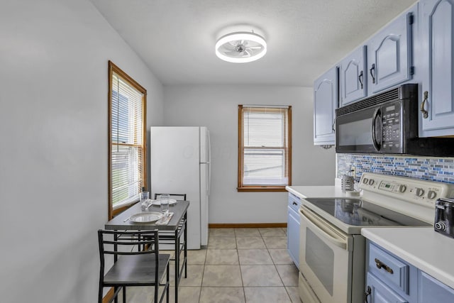 6880 Sandusky Ave, Chatfield, OH 44825 - kitchen with white appliances, light countertops, decorative backsplash, light tile patterned flooring, and baseboards