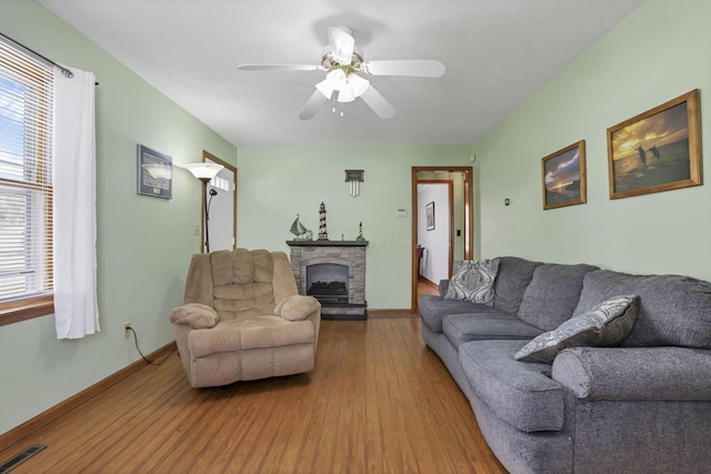 6880 Sandusky Ave, Chatfield, OH 44825 - living room featuring wood finished floors, ceiling fan, a stone fireplace, and baseboards