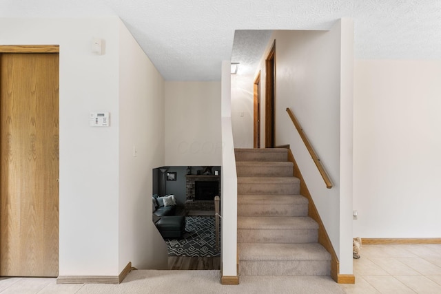 5081 Carters Corner Rd, Sunbury, OH 43074 - staircase with tile patterned flooring, a brick fireplace, a textured ceiling, and baseboards