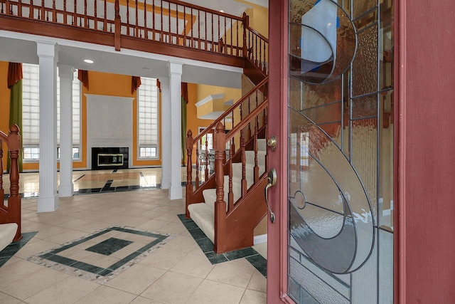 736 Eton St, Marion, OH 43302 - tiled foyer entrance featuring decorative columns, stairs, plenty of natural light, and a glass covered fireplace