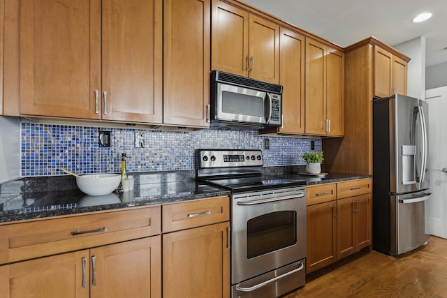 145 N High St Unit 300, Columbus, OH 43215 - kitchen with stainless steel appliances, dark wood finished floors, dark stone counters, decorative backsplash, and recessed lighting