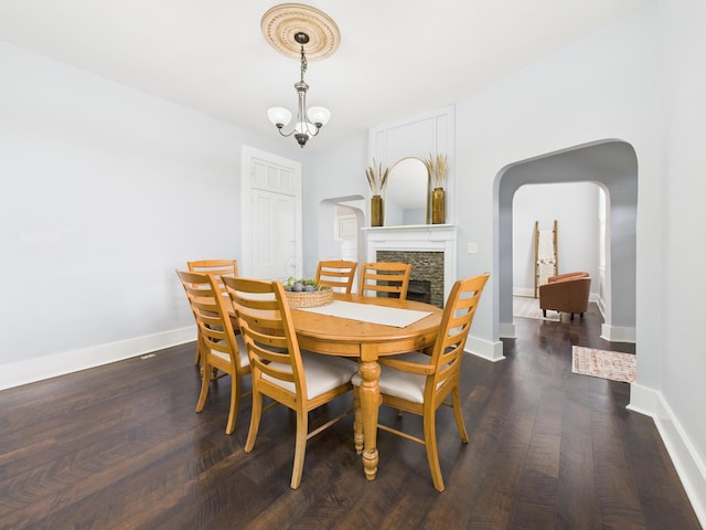 715 N Broad St, Lancaster, OH 43130 - dining room with arched walkways, a fireplace, baseboards, dark wood finished floors, and a chandelier