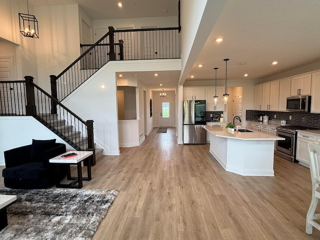 2497 Nelson Ln, Delaware, OH 43015 - kitchen featuring stainless steel appliances, a sink, light wood-style floors, white cabinets, and an island with sink