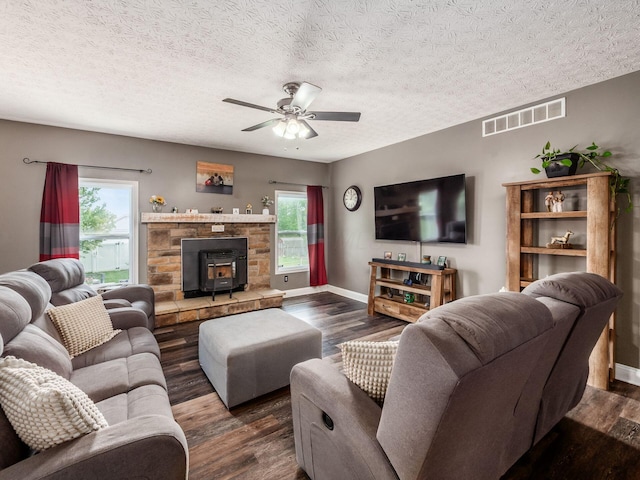 9148 Mccord Rd, Orient, OH 43146 - living room featuring a ceiling fan, a wood stove, dark wood-style floors, baseboards, and a textured ceiling