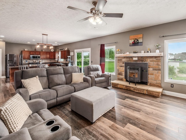 9148 Mccord Rd, Orient, OH 43146 - living room featuring a textured ceiling, dark wood-style floors, a wood stove, baseboards, and ceiling fan
