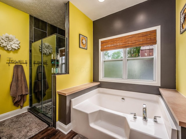 9148 Mccord Rd, Orient, OH 43146 - bathroom featuring wood finished floors, a bath, baseboards, a stall shower, and a textured ceiling