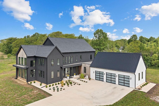 3318 S County Line Rd, Johnstown, OH 43031 - modern inspired farmhouse featuring concrete driveway, an attached garage, metal roof, and a front yard