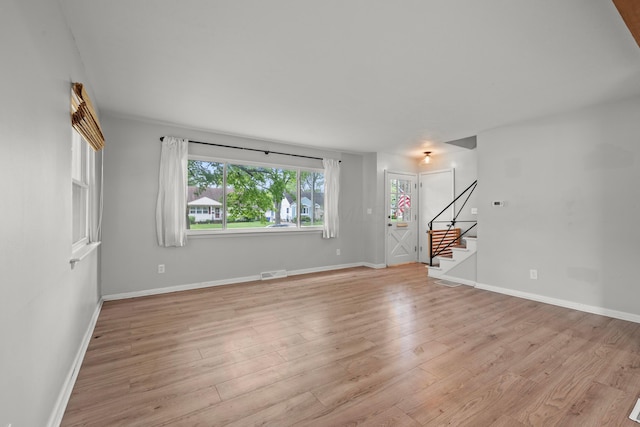 1296 Bryson Rd, Columbus, OH 43224 - unfurnished living room with stairs, light wood finished floors, and baseboards