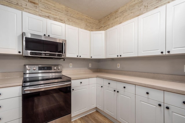 1989 Berrancher Dr, Columbus, OH 43228 - kitchen with stainless steel appliances, light countertops, white cabinets, light wood-style flooring, and a textured ceiling