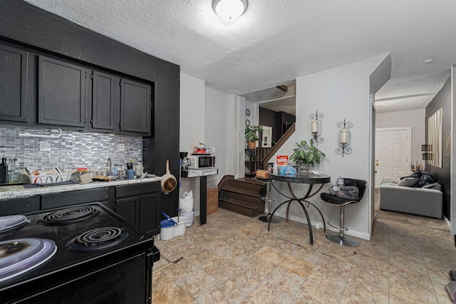 1808 S 6th St, Columbus, OH 43207 - kitchen with black / electric stove, light countertops, tasteful backsplash, a textured ceiling, and dark cabinets
