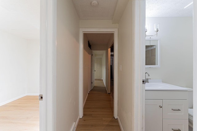 1747 E 25th Ave, Columbus, OH 43219 - hall with a sink, light wood-style floors, baseboards, and a textured ceiling