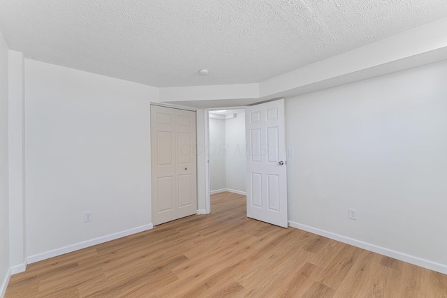 1747 E 25th Ave, Columbus, OH 43219 - unfurnished bedroom featuring light wood-style floors, baseboards, and a textured ceiling