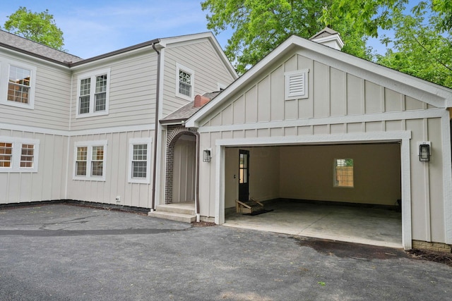 1884 W Lane Ave, Columbus, OH 43221 - view of front of property featuring board and batten siding, a shingled roof, asphalt driveway, and a garage