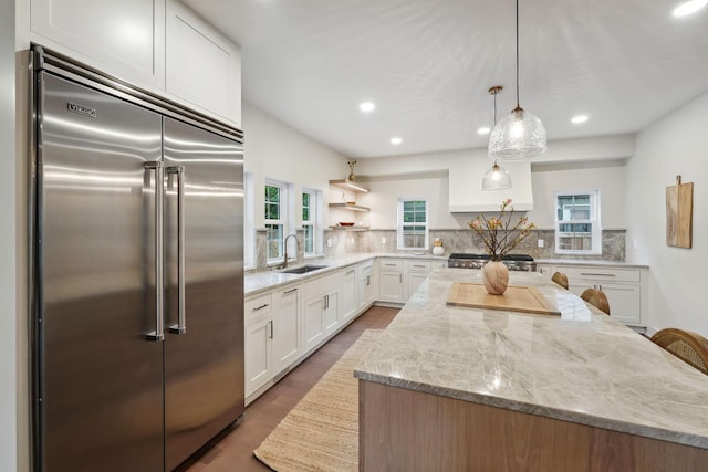 1884 W Lane Ave, Columbus, OH 43221 - kitchen with high end refrigerator, a sink, a center island, white cabinets, and light stone counters