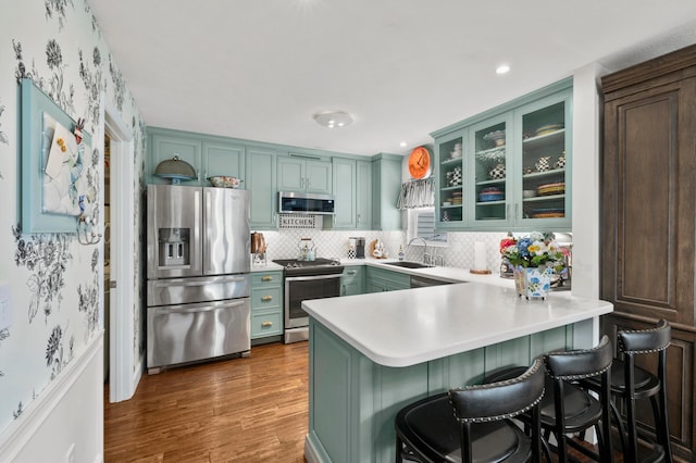4088 Sweet Shadow Ave, Columbus, OH 43230 - kitchen with appliances with stainless steel finishes, a sink, a peninsula, wood finished floors, and green cabinetry