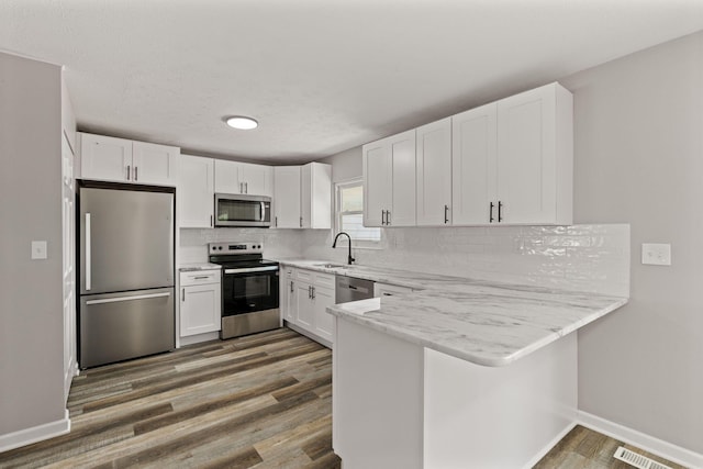 4778 Hafey Ave, Columbus, OH 43228 - kitchen with appliances with stainless steel finishes, white cabinets, a peninsula, and wood finished floors