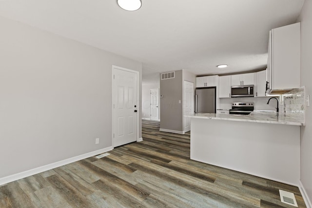 4778 Hafey Ave, Columbus, OH 43228 - kitchen featuring appliances with stainless steel finishes, white cabinets, dark wood-type flooring, a peninsula, and light stone countertops