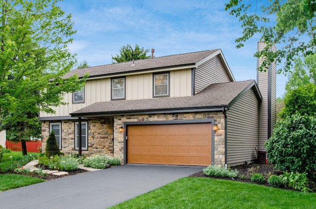 1672 Flat Rock Ct, Columbus, OH 43235 - view of front facade featuring stone siding, asphalt driveway, a chimney, roof with shingles, and board and batten siding