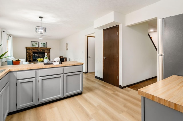 1672 Flat Rock Ct, Columbus, OH 43235 - kitchen featuring freestanding refrigerator, gray cabinetry, light wood finished floors, a brick fireplace, and light countertops
