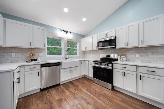 13404 Maple Rd NE, Thornville, OH 43076 - kitchen featuring appliances with stainless steel finishes, vaulted ceiling, tasteful backsplash, a sink, and white cabinets