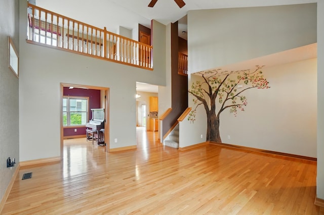790 Salinger Dr, Lithopolis, OH 43136 - unfurnished living room featuring a ceiling fan, a towering ceiling, stairway, light wood finished floors, and baseboards