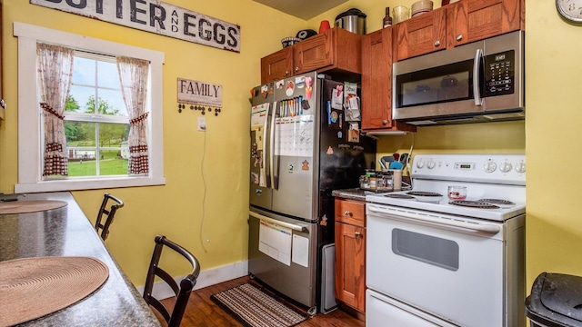 12151 State Route 93 N, Logan, OH 43138 - kitchen with appliances with stainless steel finishes, dark wood-type flooring, dark countertops, brown cabinetry, and baseboards