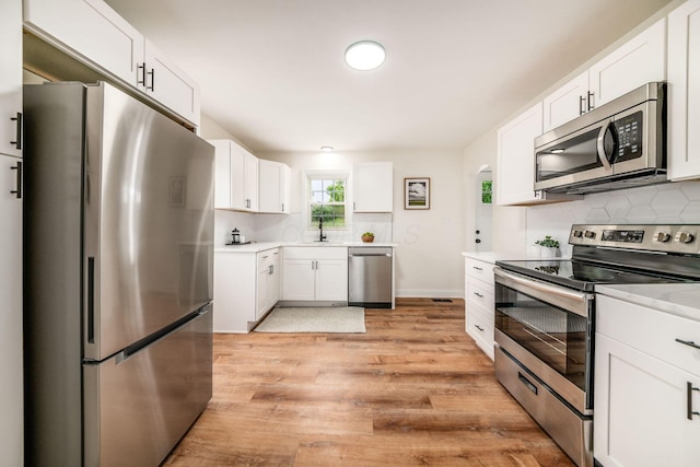 3232 Williams Rd, Columbus, OH 43207 - kitchen with stainless steel appliances, light wood finished floors, backsplash, light countertops, and a sink