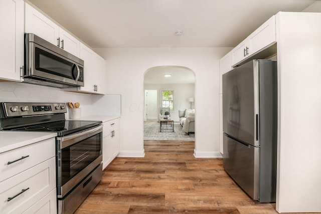 3232 Williams Rd, Columbus, OH 43207 - kitchen with appliances with stainless steel finishes, arched walkways, wood finished floors, and white cabinetry