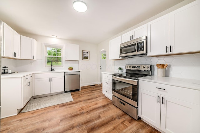 3232 Williams Rd, Columbus, OH 43207 - kitchen featuring appliances with stainless steel finishes, a sink, light wood-style flooring, and decorative backsplash