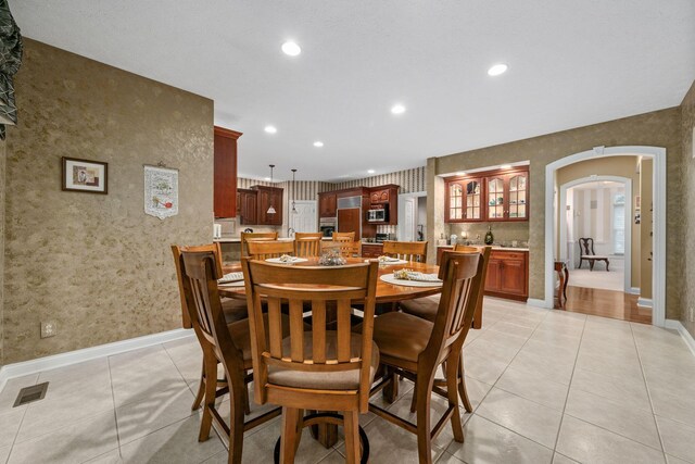 7607 Stone Ridge Dr, Springboro, OH 45066 - dining space featuring arched walkways, recessed lighting, wallpapered walls, baseboards, and light tile patterned flooring