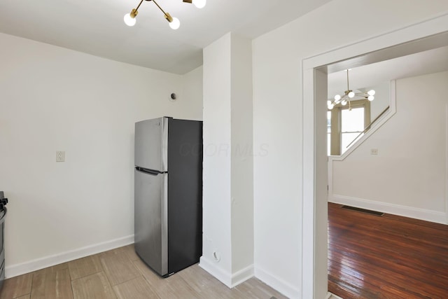 399 E Woodrow Ave, Columbus, OH 43207 - kitchen with freestanding refrigerator, a chandelier, light wood finished floors, and range