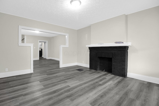 162 Columbian Ave Unit 164, Columbus, OH 43223 - unfurnished living room featuring wood finished floors, a textured ceiling, baseboards, and a brick fireplace