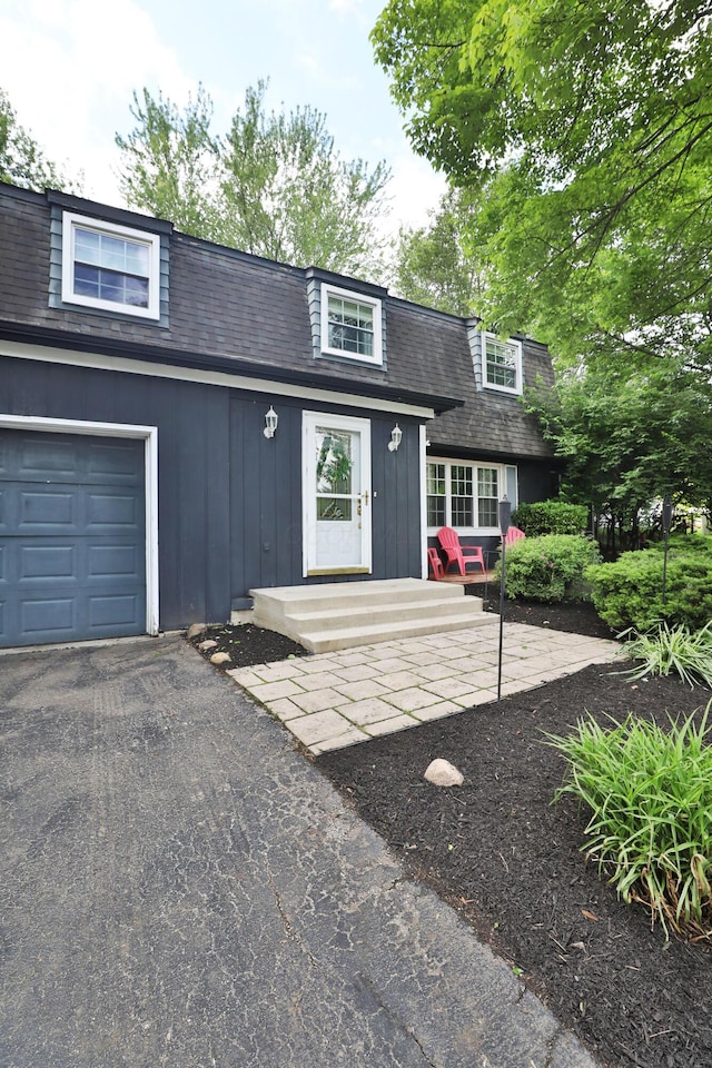 5255 Dory Ln, Columbus, OH 43235 - view of front of home featuring board and batten siding, a shingled roof, asphalt driveway, and a garage